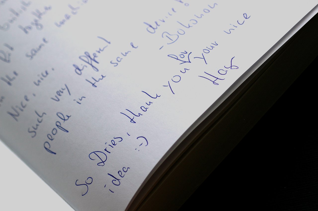 A handwritten message in a book thanking Dries for an idea, written in blue ink on white pages.
