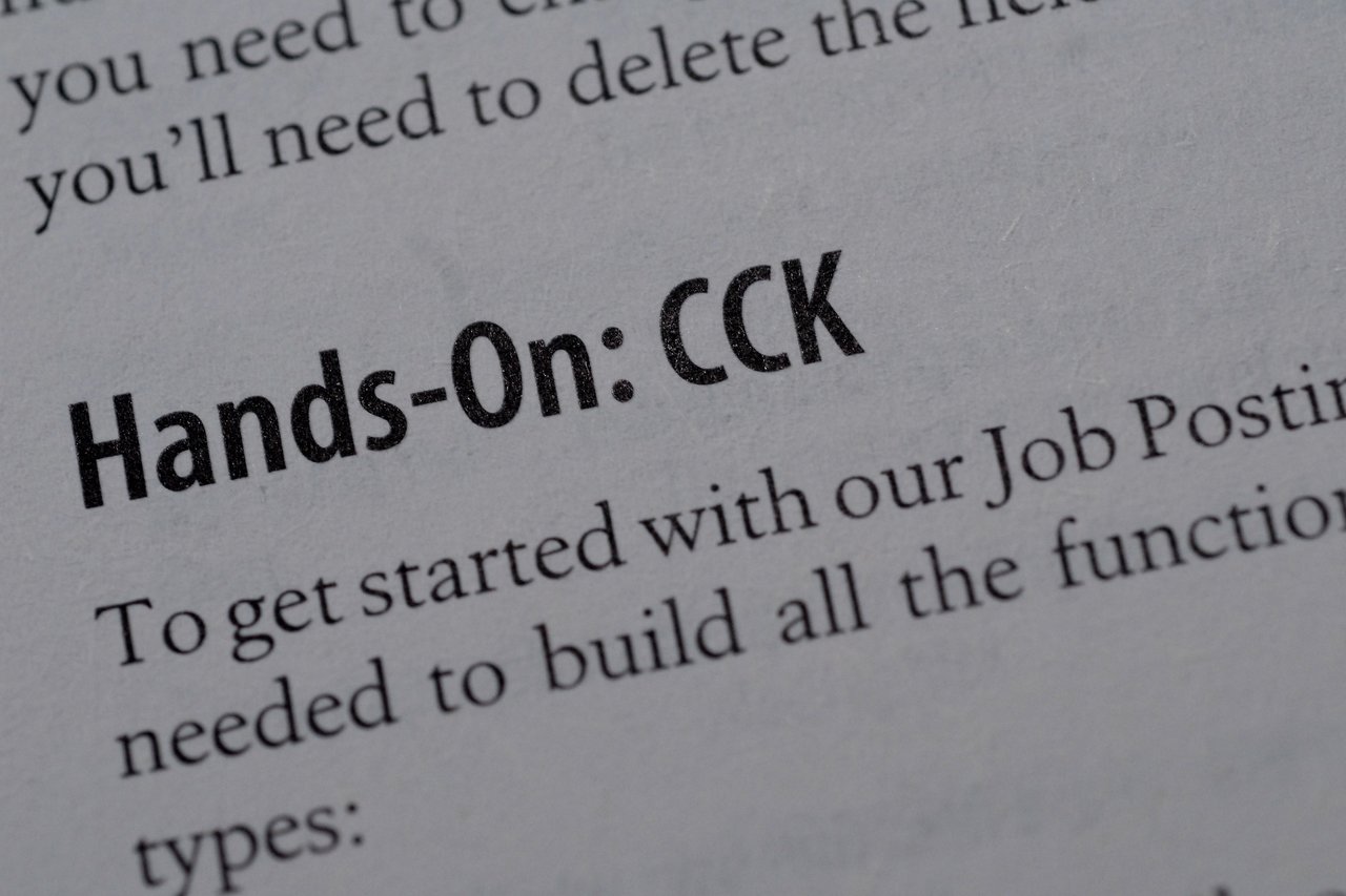 Close-up of a book page with the heading "Hands-On: CCK" in bold, discussing Drupal content creation.