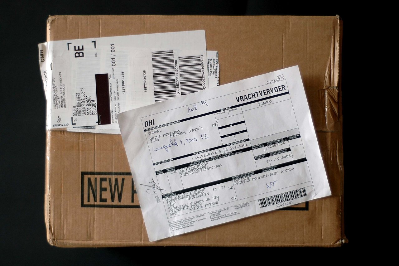 A sealed cardboard package with shipping labels and documents attached, indicating delivery details for a book order.
