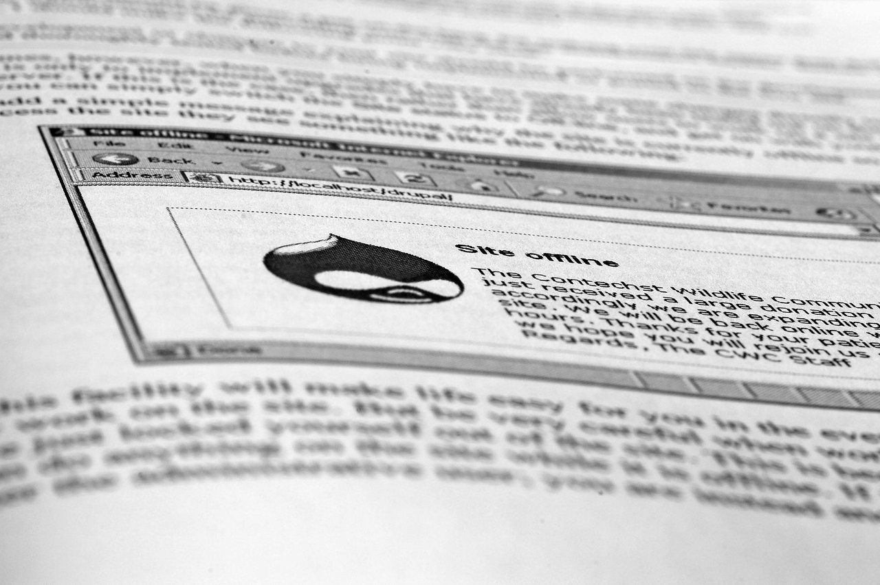 A printed book page shows a screenshot of a Drupal website with a "Site offline" message and logo.