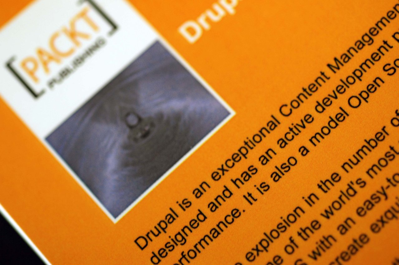 Close-up of a Packt Publishing book about Drupal, showing the logo, an image, and descriptive text on the cover.