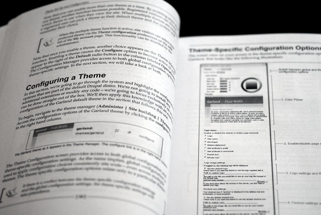 Open book showing a guide on configuring themes in Drupal 5, with text and screenshots explaining theme settings.