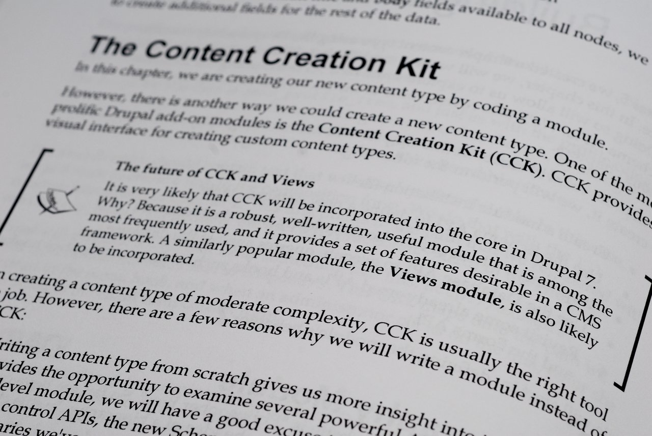 Close-up of a book page discussing the Content Creation Kit (CCK) and Views module in Drupal development.