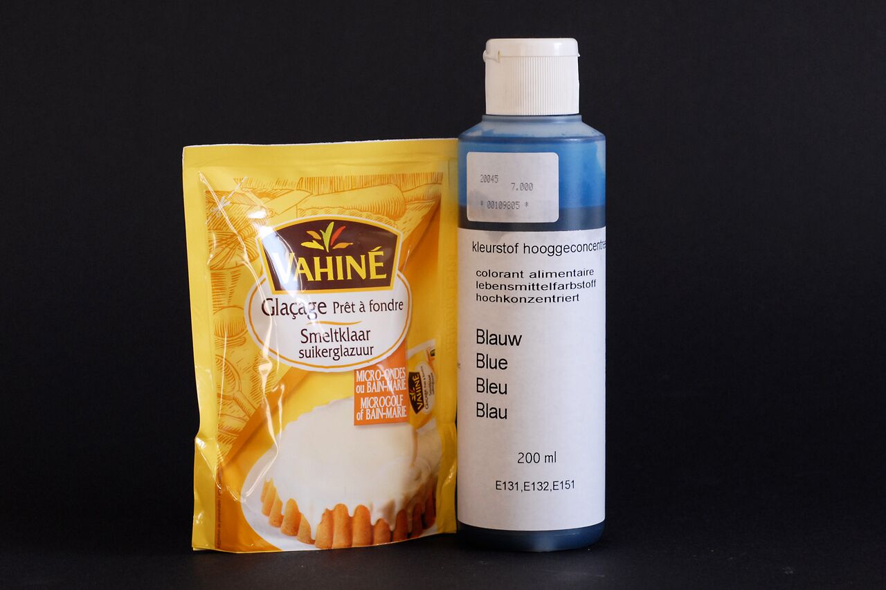A packet of white frosting and a bottle of blue food coloring for mixing blue frosting.