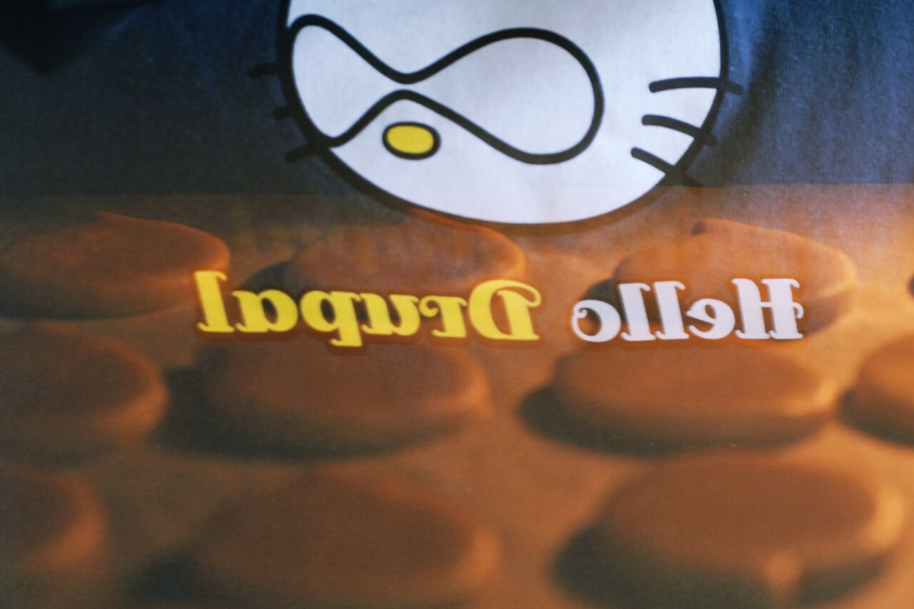 A tray of cookies baking in the oven, with a reflection of a Drupal-themed t-shirt on the glass.