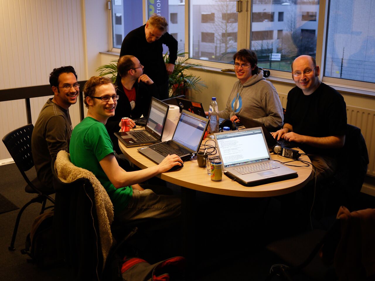 A group of people collaborating on Drupal 7 core and Views upgrade at a coding sprint, using laptops.
