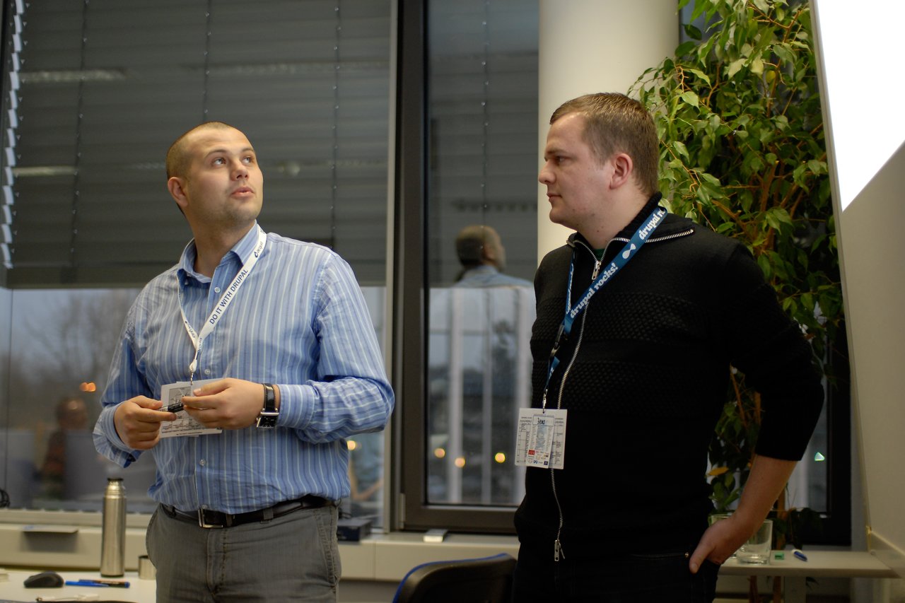 Two presenters from Propeople stand in front of a screen, discussing their work at DrupalCamp Cologne 2009.