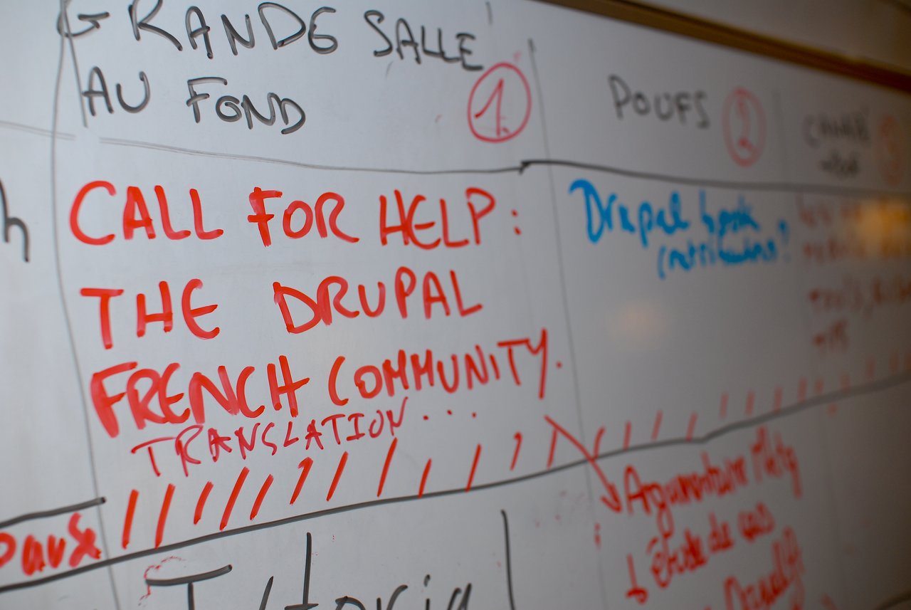 A whiteboard with "Call for help: The Drupal French community translation" written in red marker, requesting assistance.