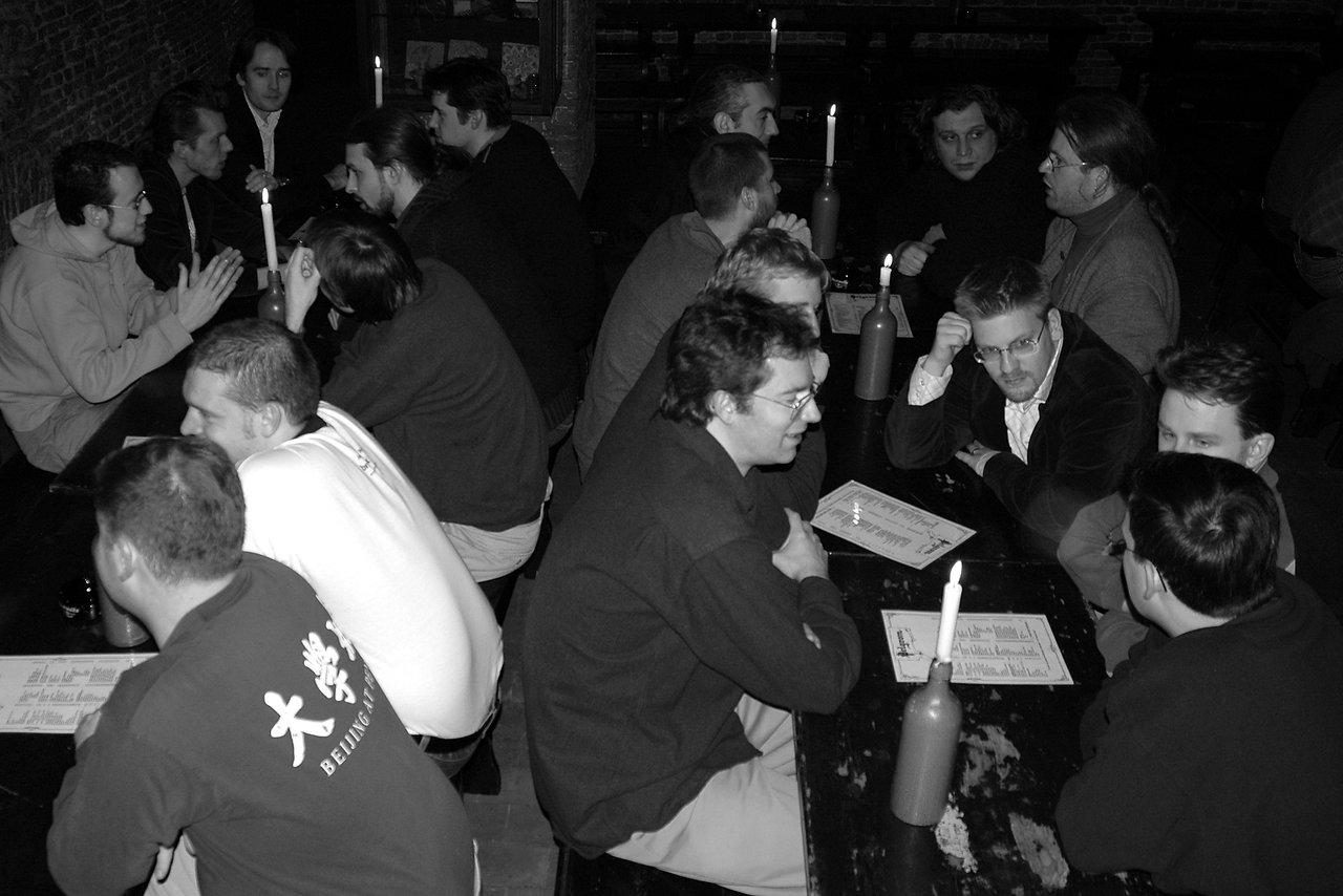 A group of Drupal developers gathered around tables, engaged in discussions and collaboration at a dimly lit venue.