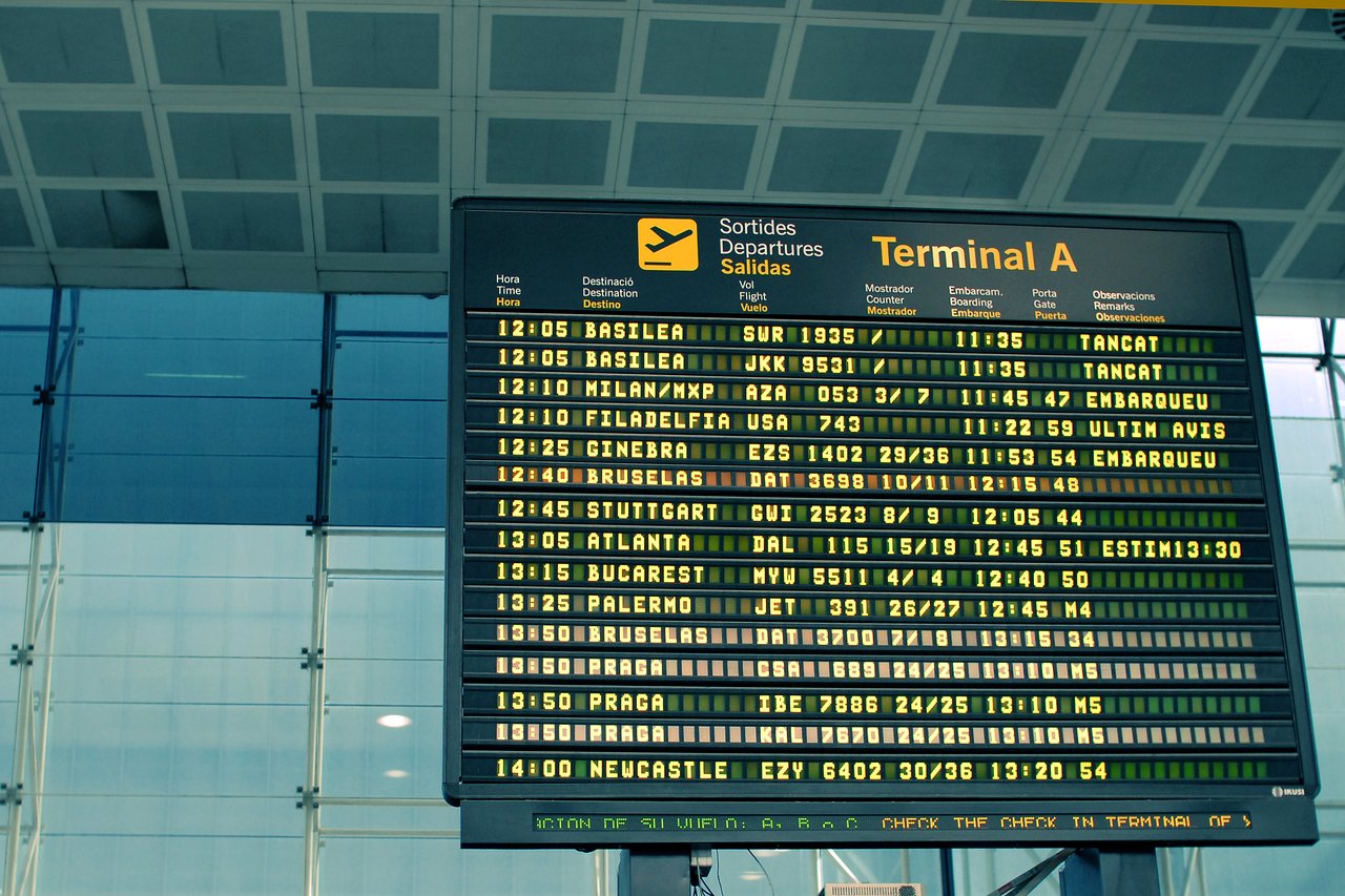 An airport departure board displaying flight times, destinations, and statuses at Terminal A in Barcelona.