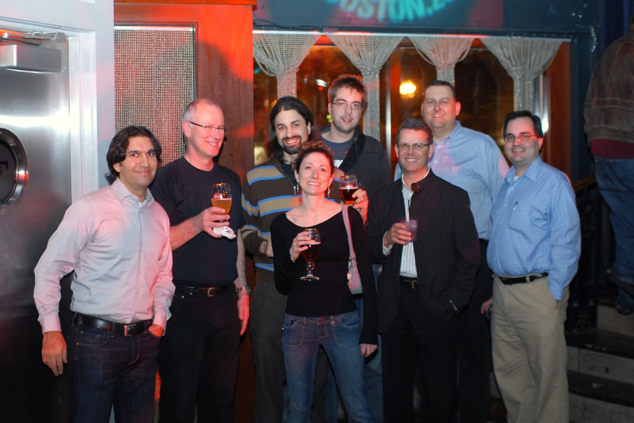 A group of Acquia employees smiling and holding drinks at the company's launch party in Boston.