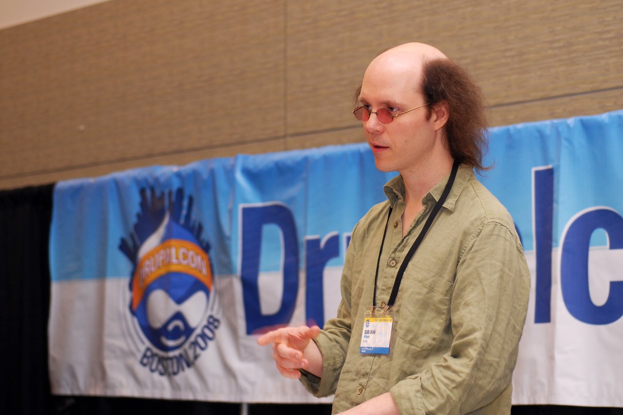A speaker wearing a name badge gestures while presenting at DrupalCon Boston 2008.