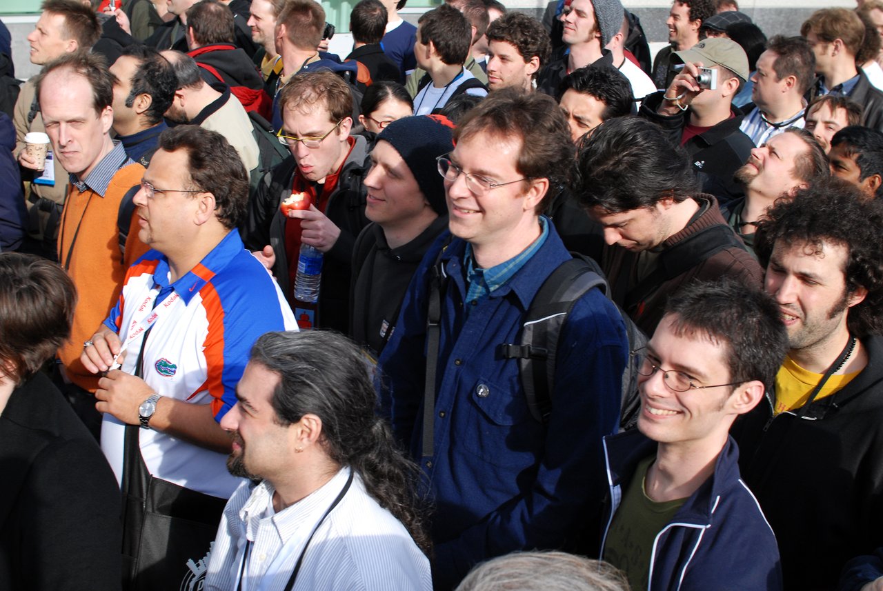 A large group of people at DrupalCon Boston 2008, standing close together, smiling, and engaging with the event.