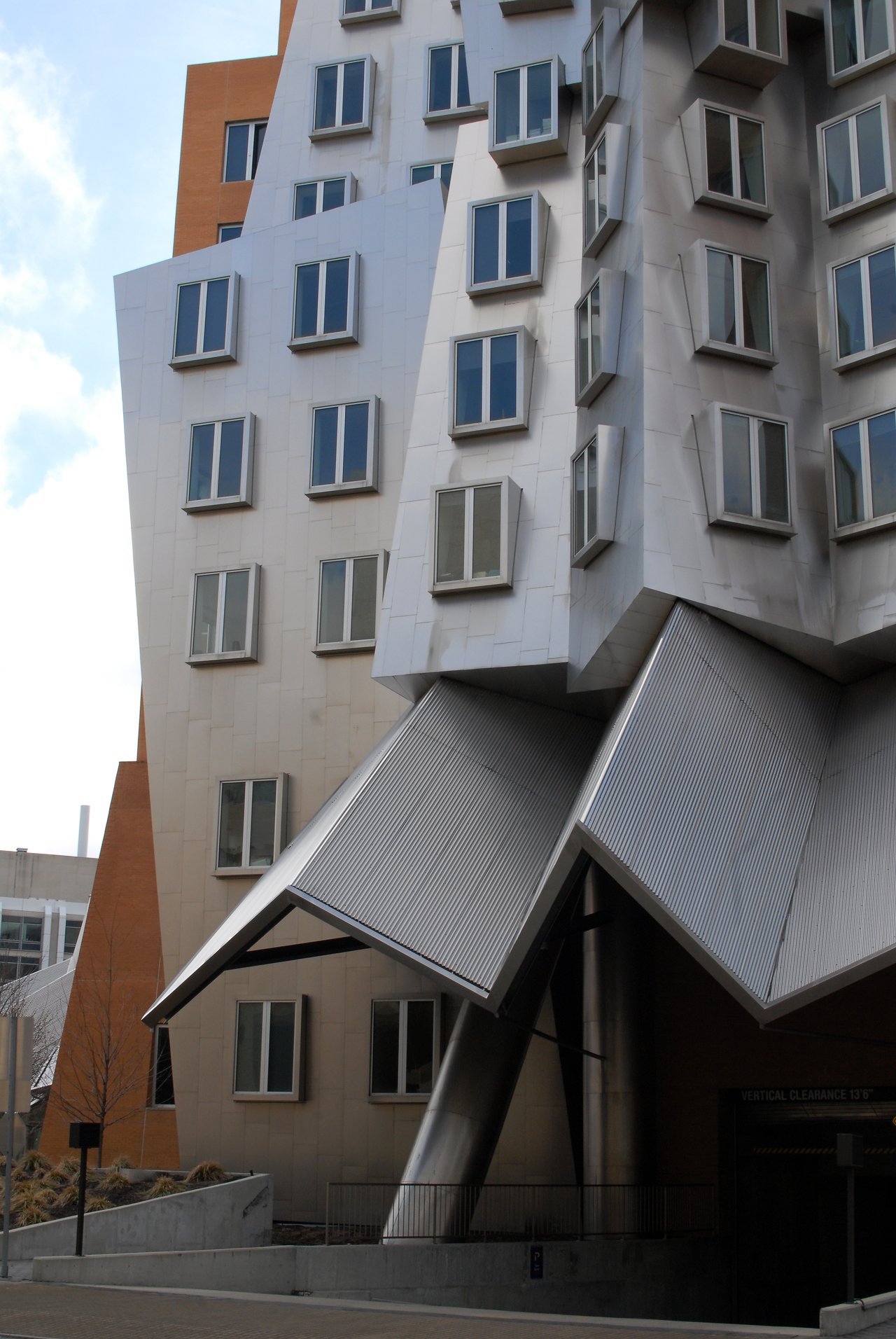A uniquely designed modern building with irregular shapes and reflective metal surfaces at MIT.