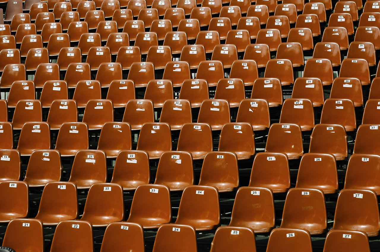 Rows of empty brown plastic chairs with numbered labels, neatly arranged in a structured seating area.
