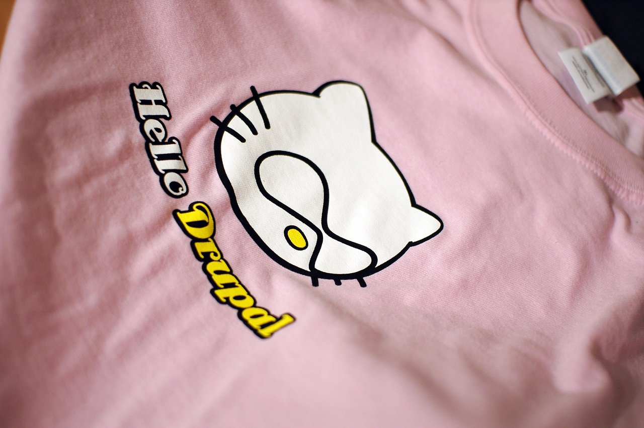 Pink T-shirt with a "Hello Drupal" design featuring a stylized cat face inspired by the Drupal logo.