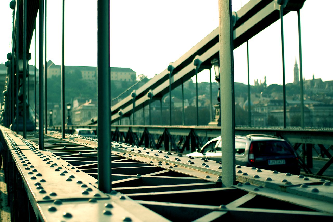 Close-up of the Széchenyi Chain Bridge in Budapest, showing its metal structure with cars driving across.