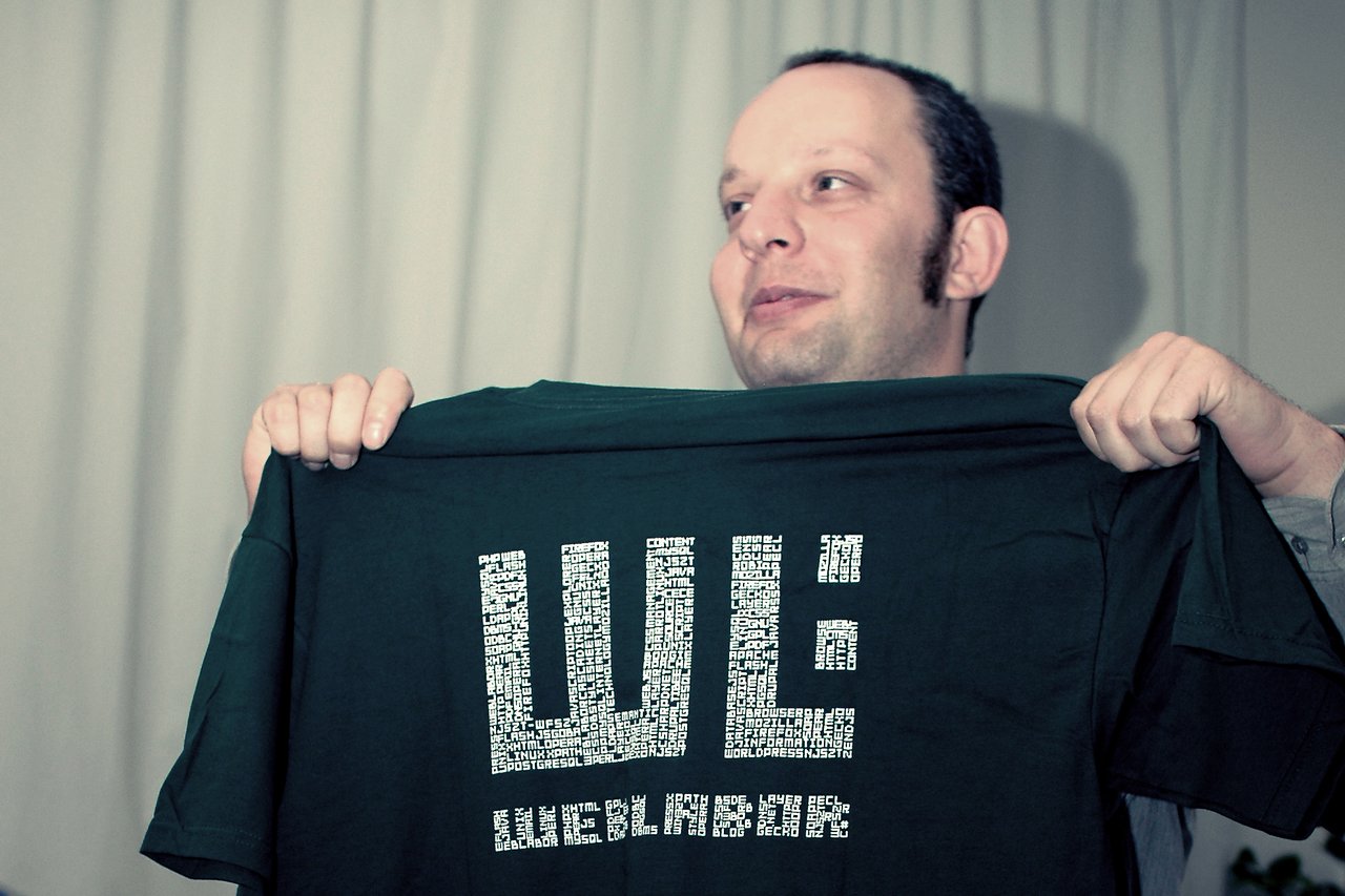 A person holds up a dark green T-shirt with "Weblabor" printed in white text.