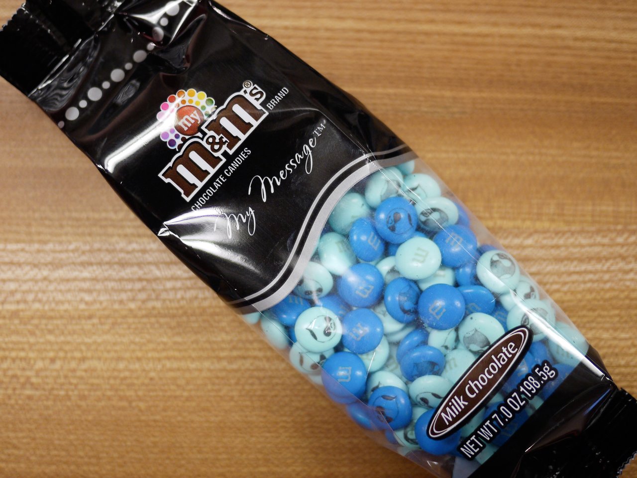 A bag of custom blue and light blue M&amp;M's featuring the Drupal logo, labeled as milk chocolate.