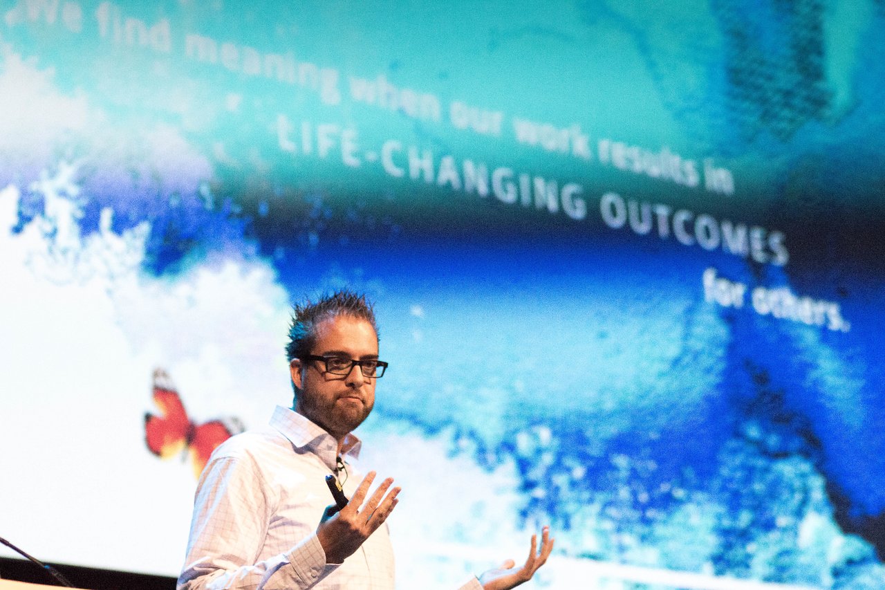 A speaker on stage at DrupalCon Dublin 2016, gesturing while presenting in front of a large screen.