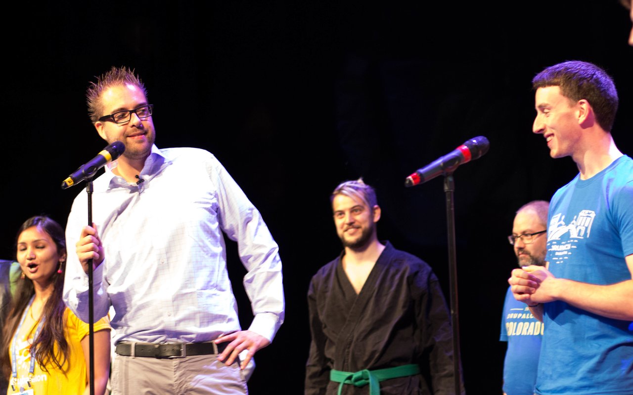 Several people stand on stage at DrupalCon Dublin 2016, speaking into microphones and engaging with the audience.