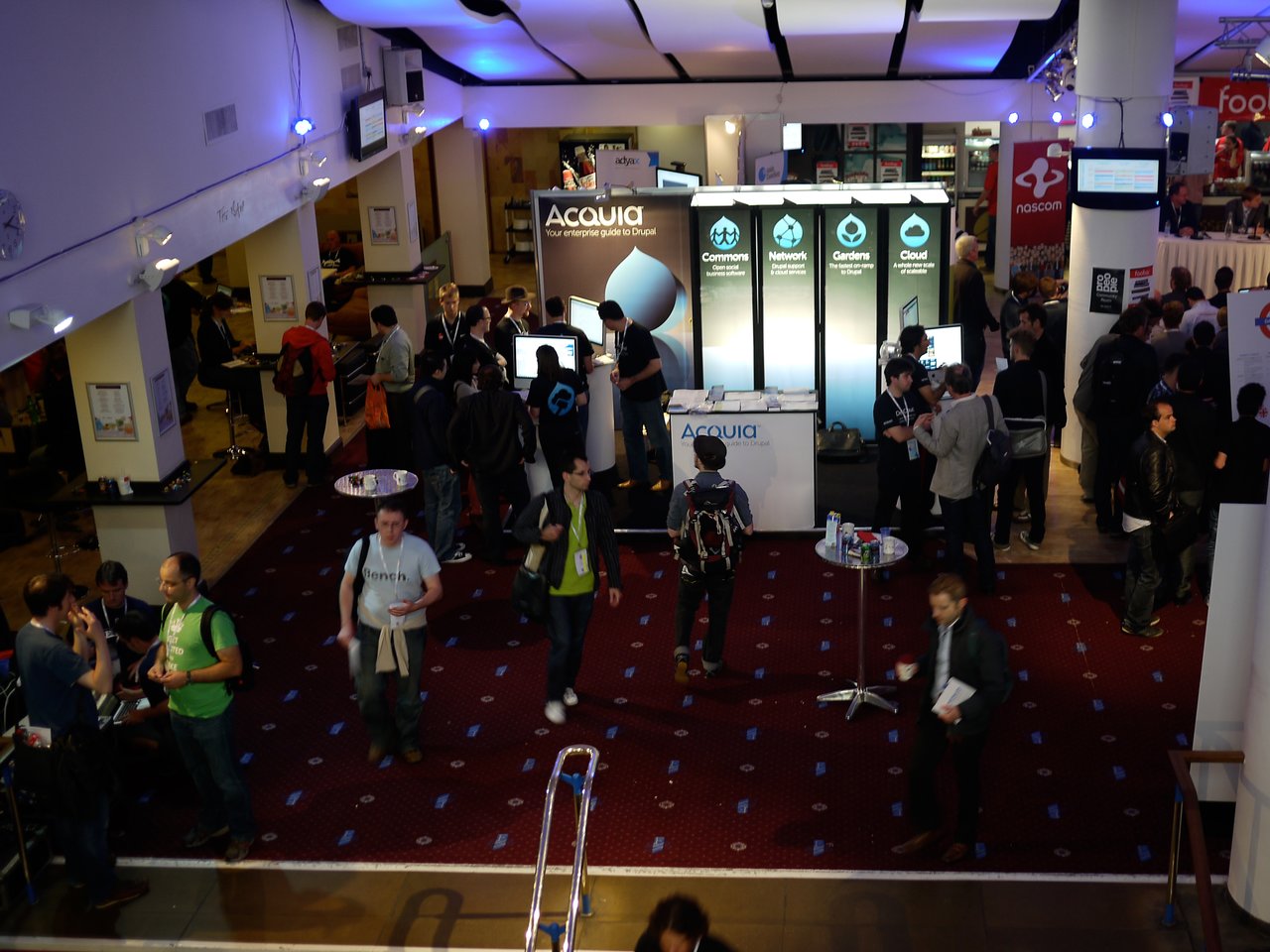 People gather around the Acquia booth at DrupalCon London 2011, engaging in discussions and exploring displayed information.
