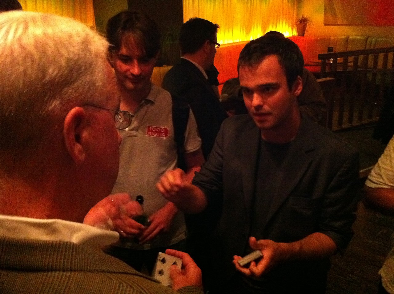 A magician performs a card trick for a small group at the Acquia customer party during DrupalCon London 2011.