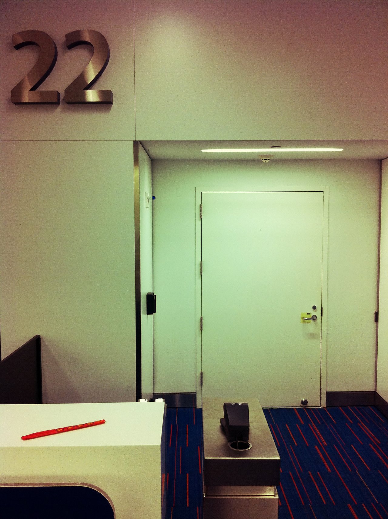 A closed airport gate at JFK with a white door and gate number 22 on the wall.