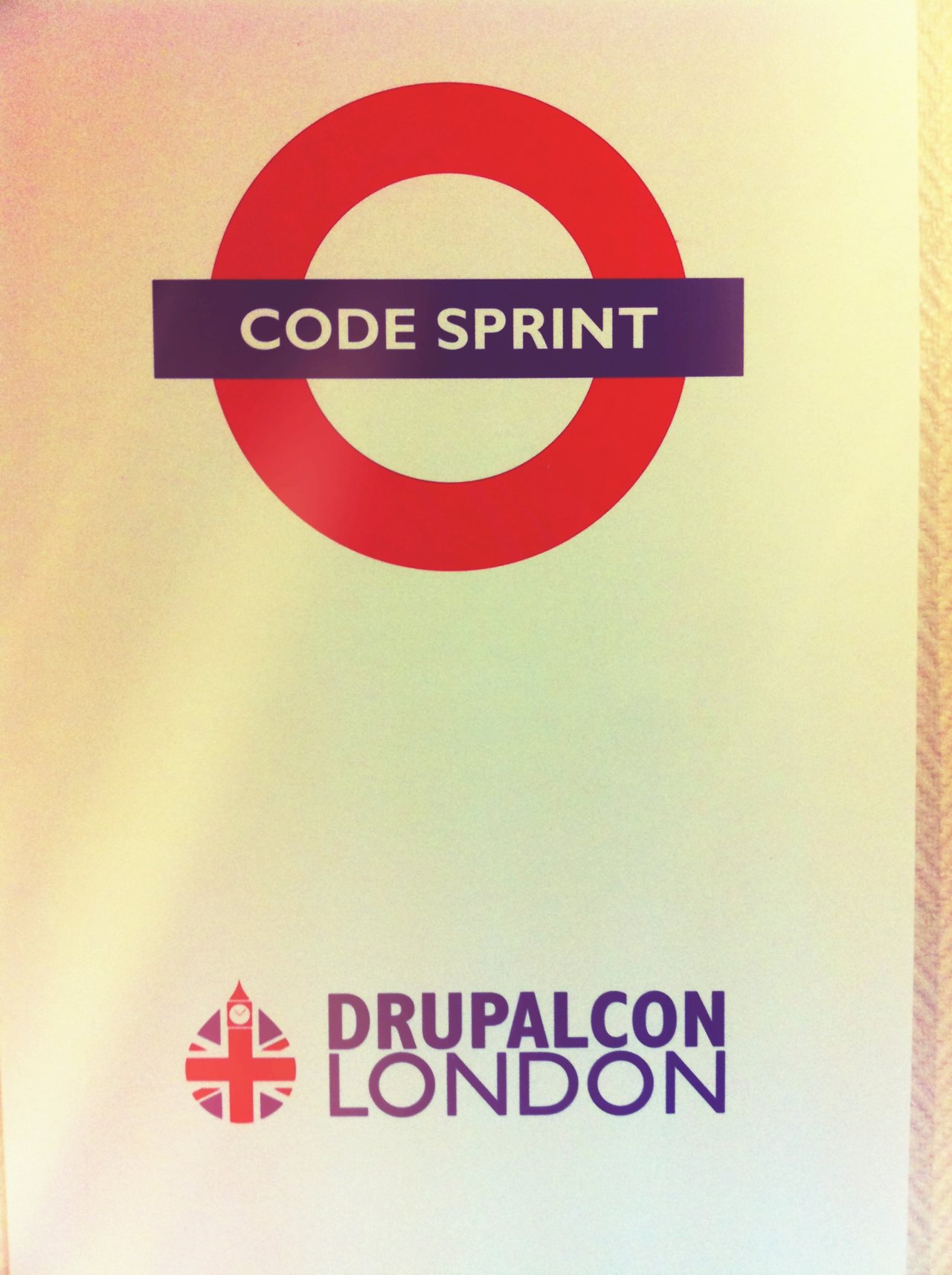 Sign with "Code Sprint" inside a red circle, and "DrupalCon London" logo below, indicating a coding event.