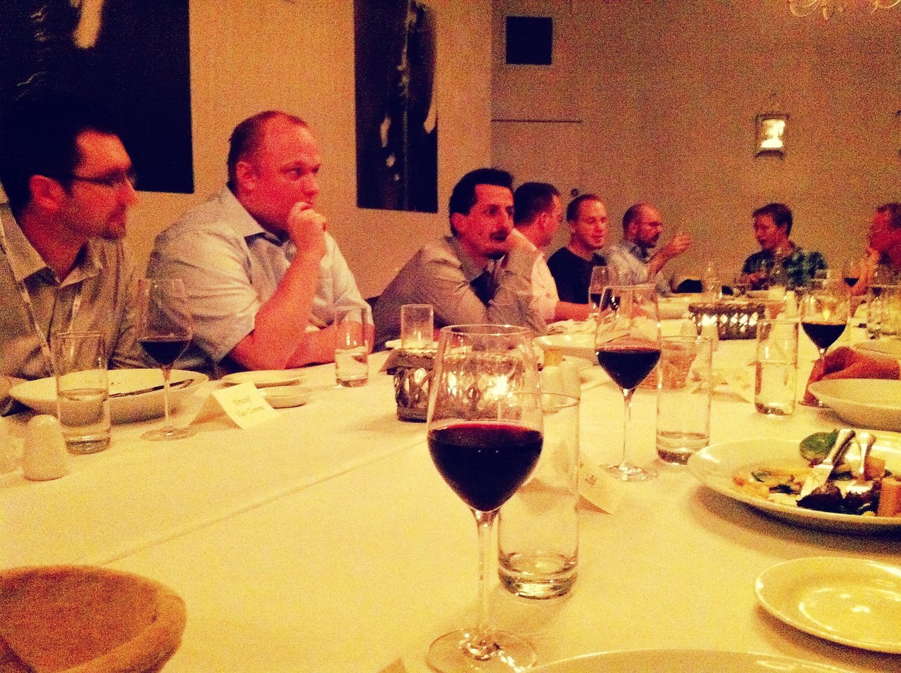 A group of people seated around a long table, engaged in conversation during a dinner gathering.