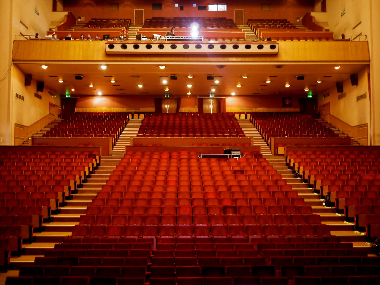 Large auditorium with rows of red seats facing a stage.