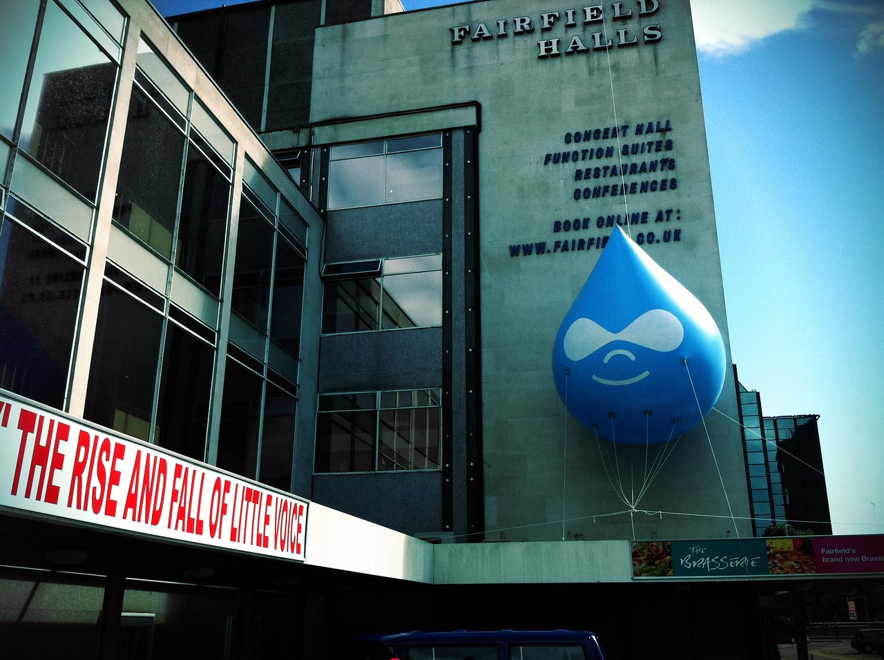 A large blue Drupal logo balloon is attached to the exterior of a modern building named Fairfield Halls.