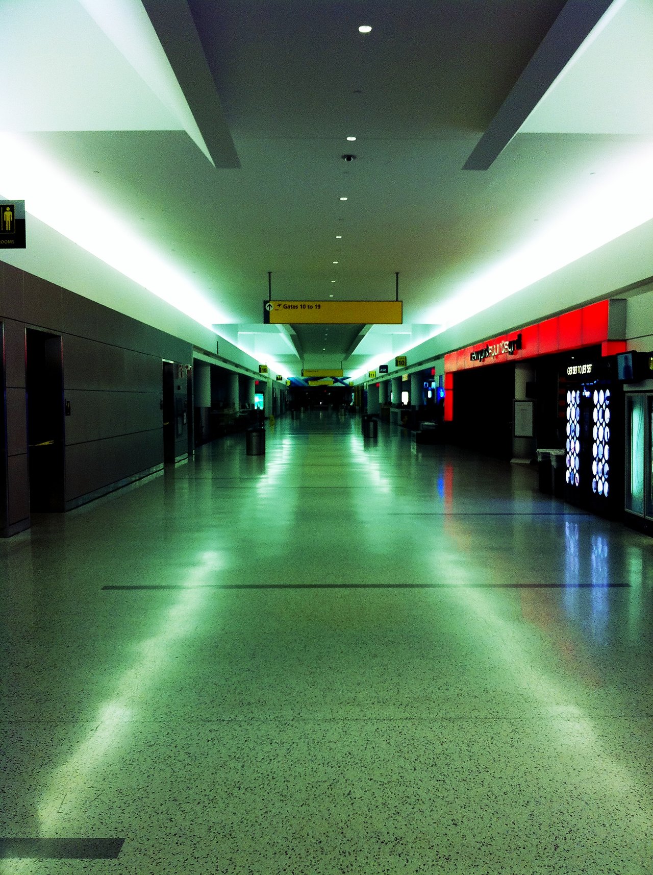 A mostly empty airport terminal with bright overhead lighting.