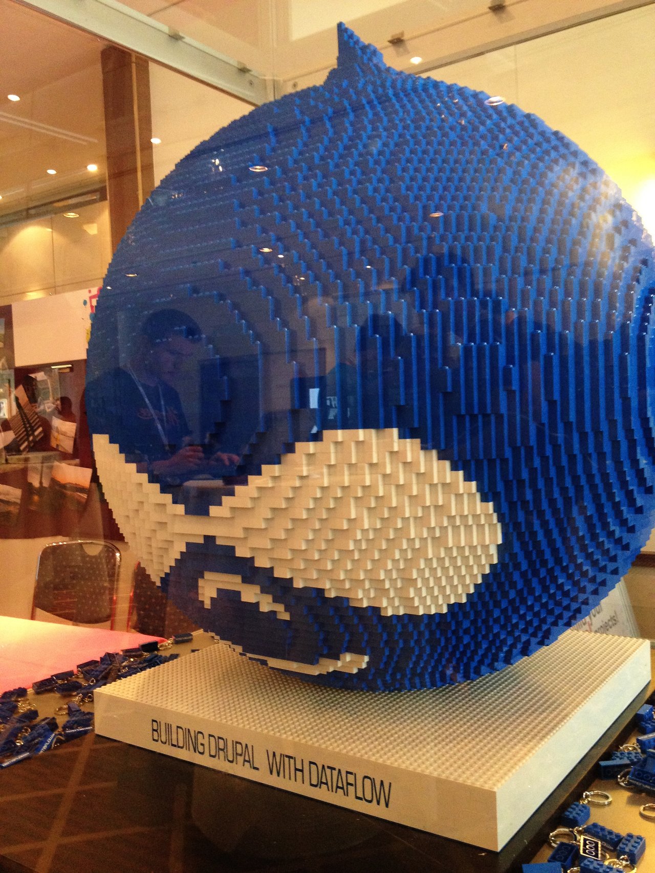 A large Drupal logo made from blue and white LEGO bricks is displayed on a stand at DrupalCon Munich 2012.