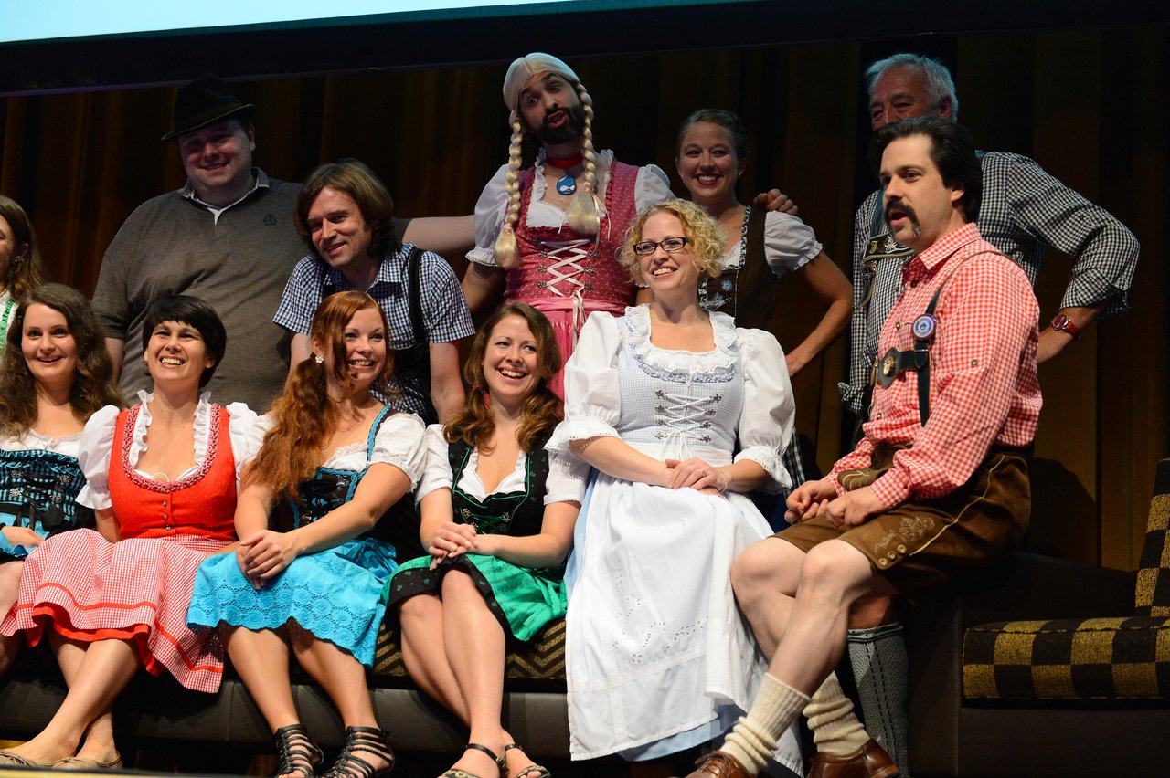 A group of people in traditional Bavarian clothing pose together and smile during a DrupalCon Munich 2012 session.