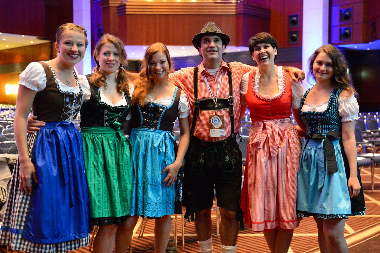 A group of six people in traditional Bavarian clothing pose together and smile at the camera during the event.