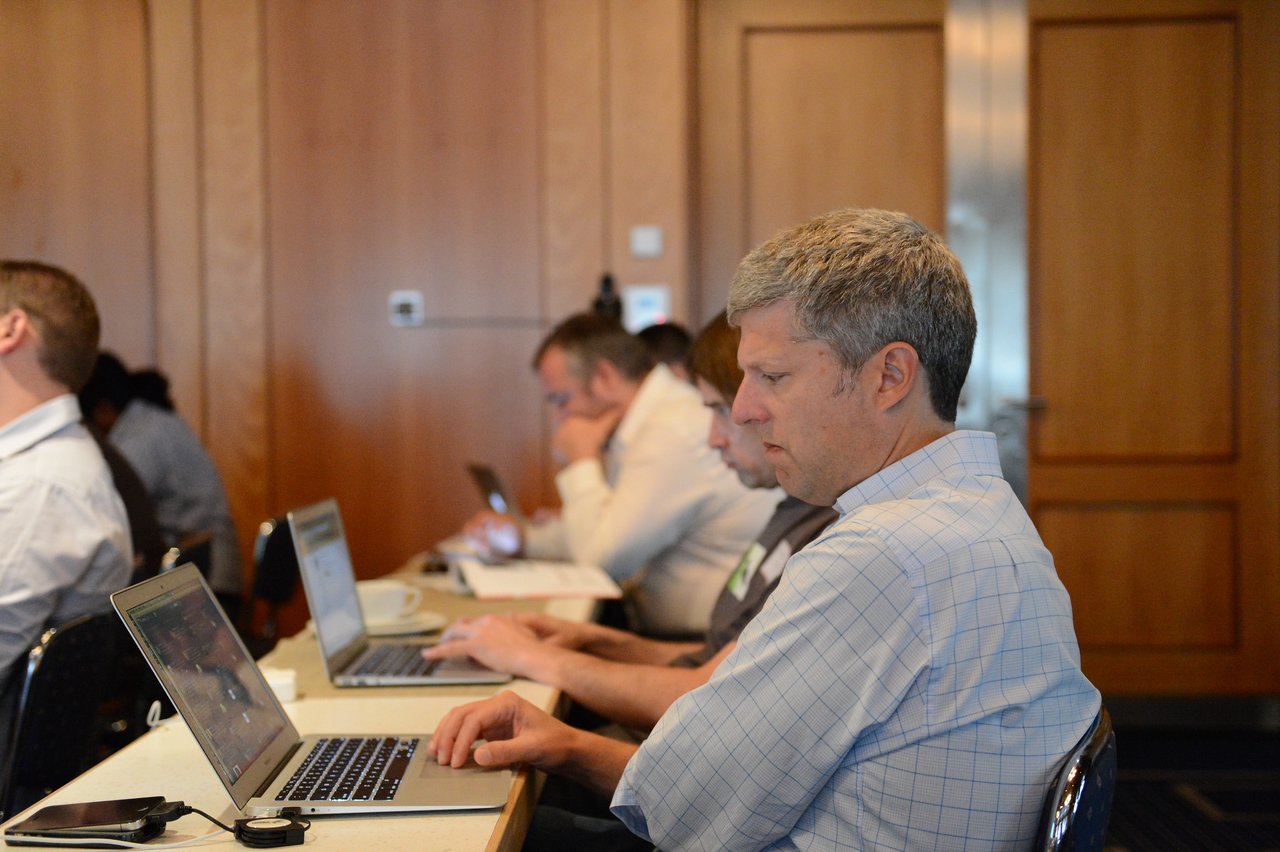 People attending a Drupal conference, focused on their laptops and taking notes during a session.