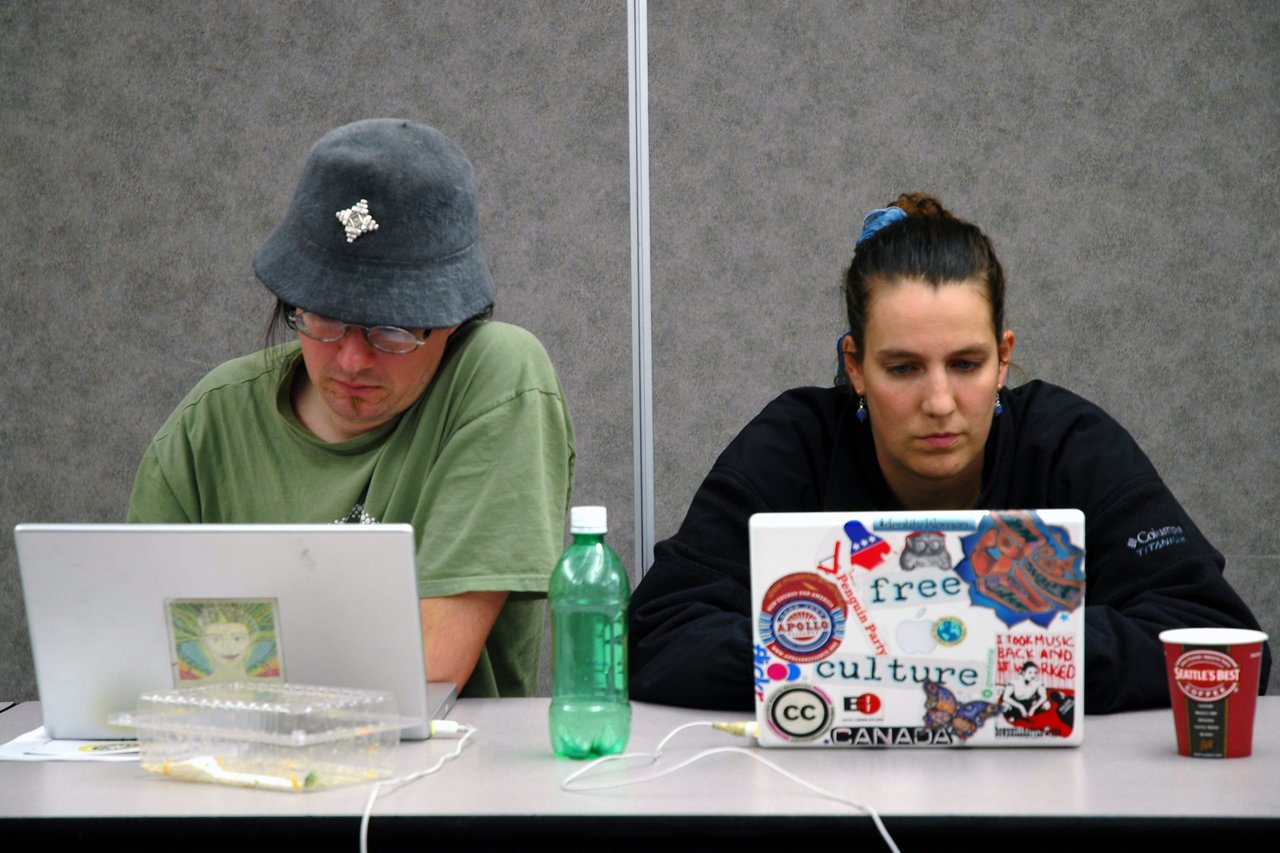 Two people sitting at a table, focused on their laptops during the Drupal conference.