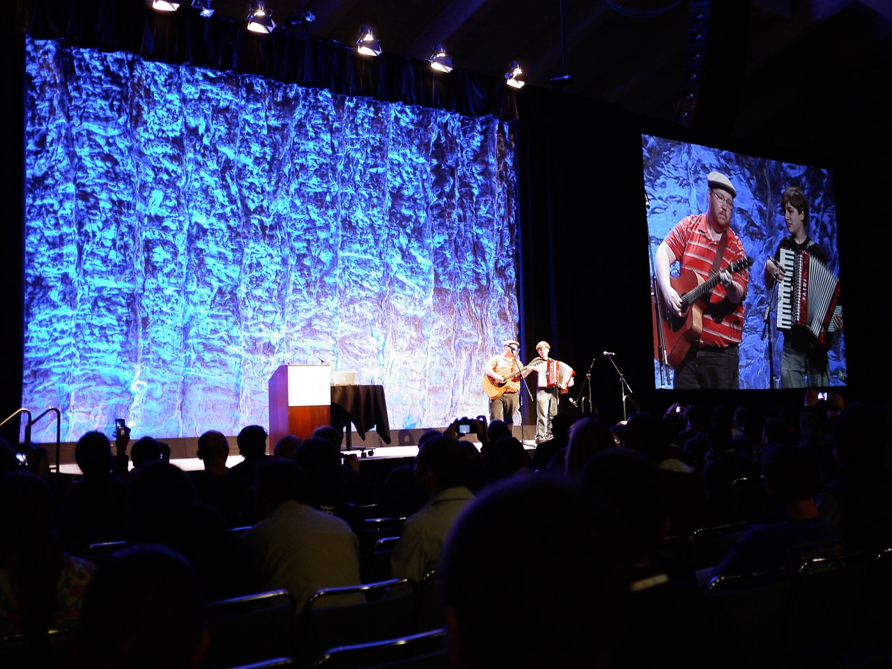 Two musicians perform on stage with a guitar and accordion during the closing song at DrupalCon San Francisco 2010.