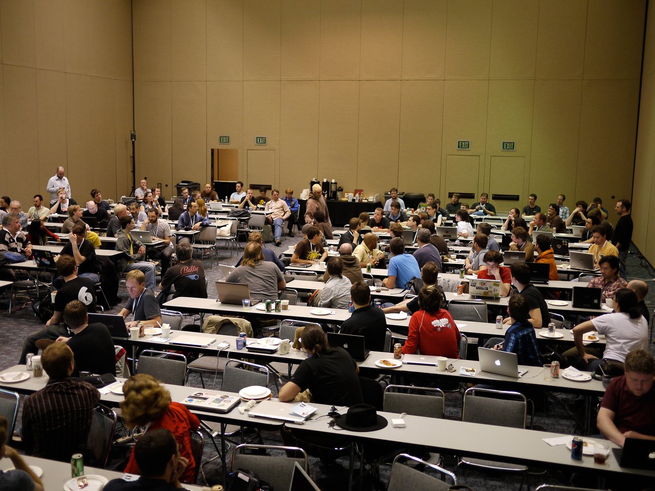 A large group of people in a conference room, discussing and working on laptops during a core developer summit.