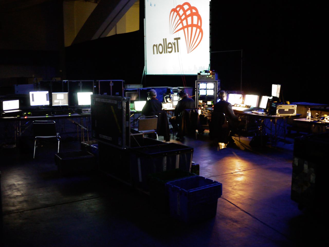 People working at computer stations backstage, managing technical equipment and screens before a keynote presentation at DrupalCon 2010.