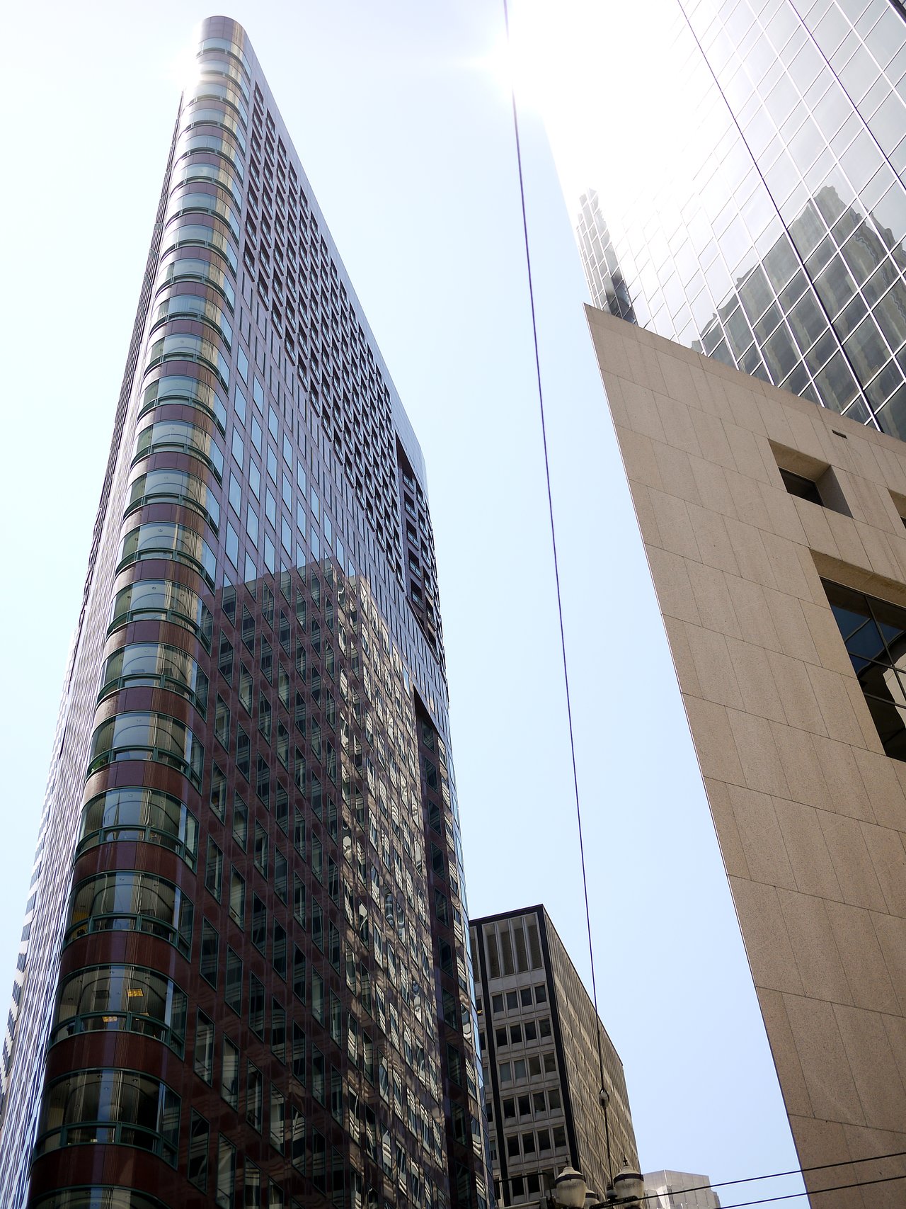 Tall modern buildings with glass windows reflecting sunlight, viewed from below on a San Francisco street.