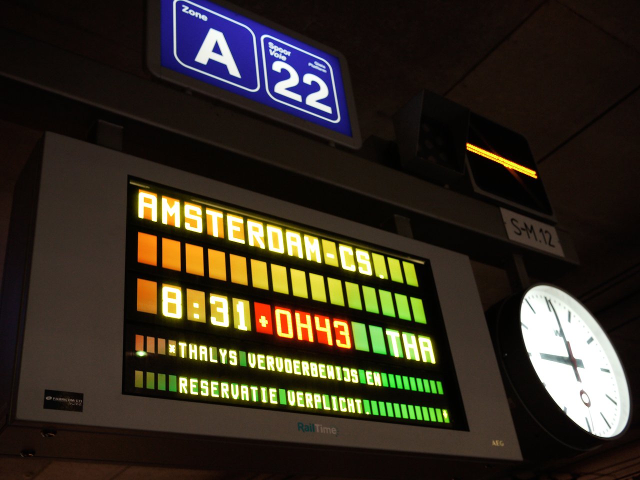 Train departure board shows a 43-minute delay for a Thalys train to Amsterdam at platform A22.