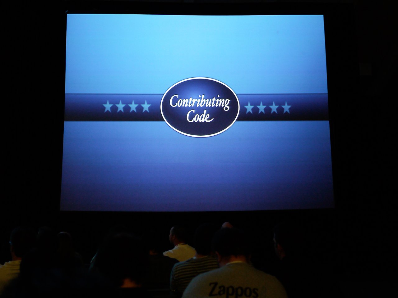 A presentation slide displays "Contributing Code" at DrupalCon San Francisco 2010, with an audience watching.