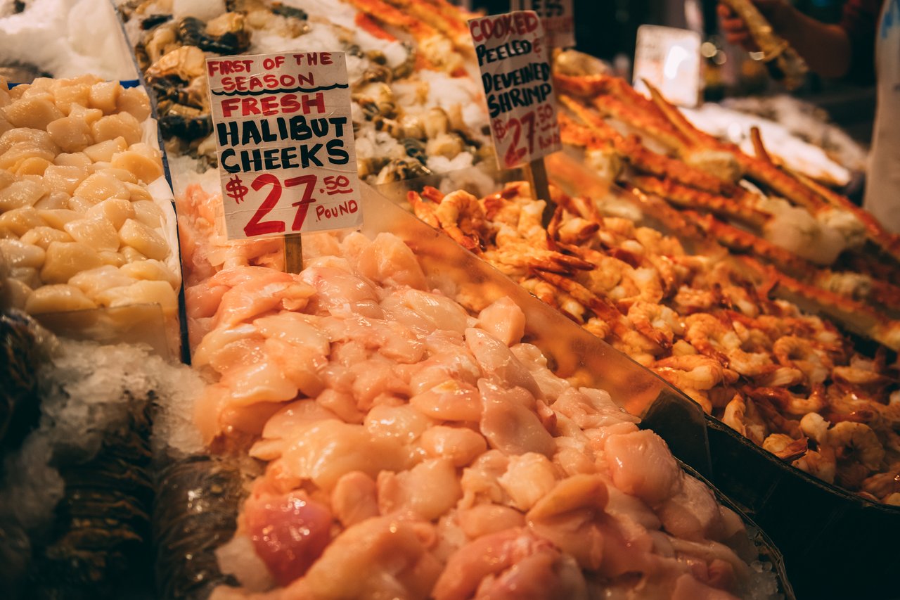 Fresh seafood at the Seattle public market, featuring halibut cheeks, shrimp, and other shellfish on ice.