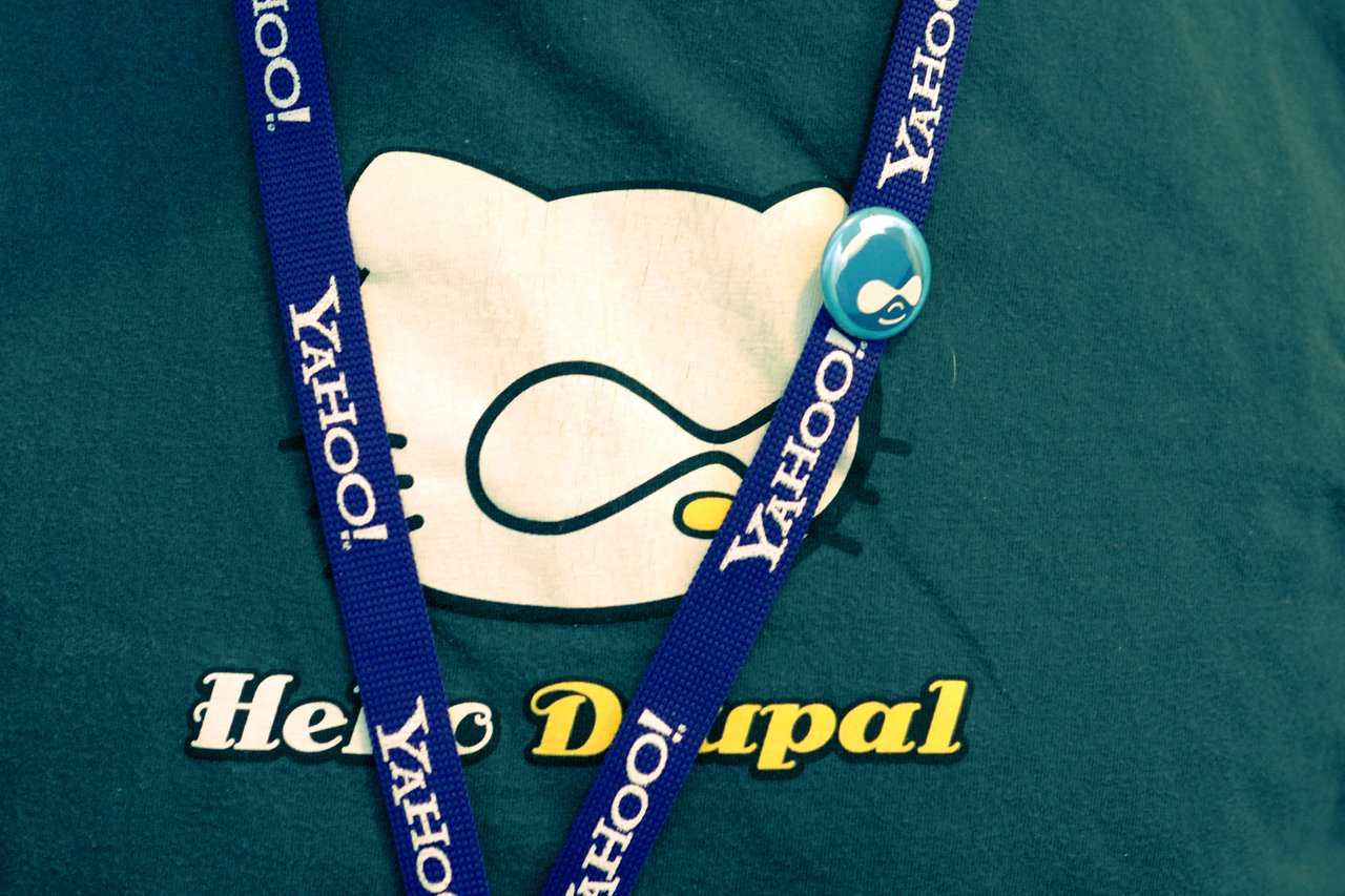 A person wearing a "Hello Drupal" shirt, a Yahoo! lanyard, and a Drupal logo button.