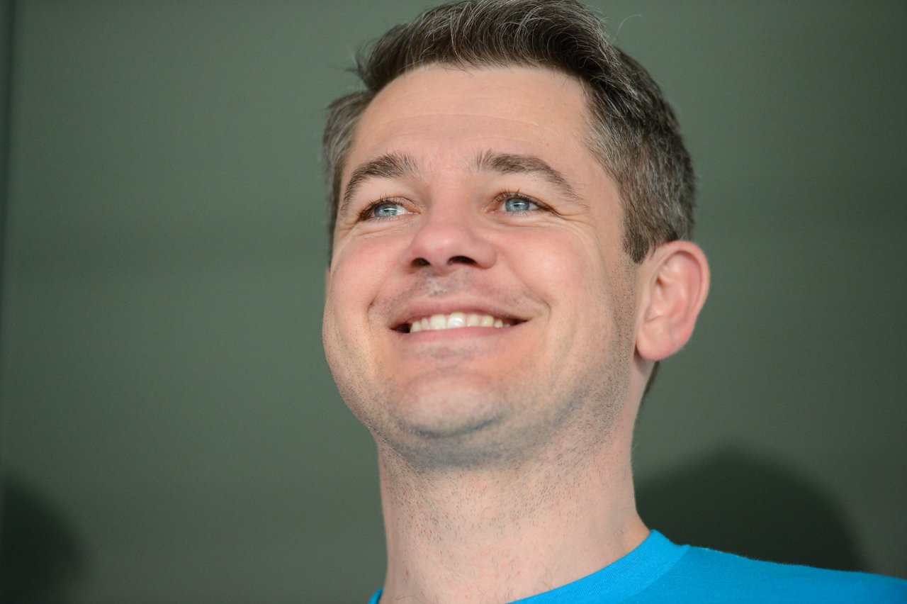 A man in a blue shirt smiles while looking slightly upward.