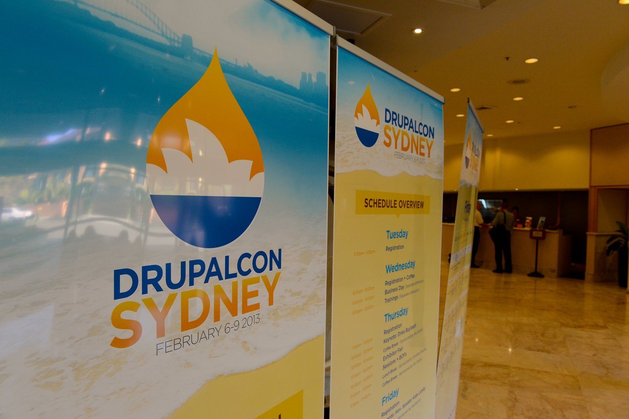 Banners display the DrupalCon Sydney 2013 logo and event schedule in a conference venue.