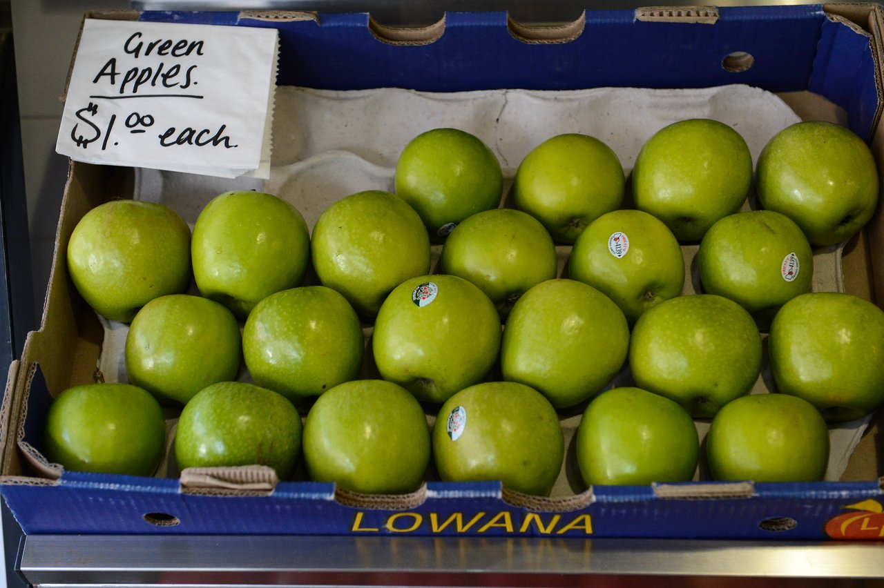 A box of green apples for sale, priced at $1.