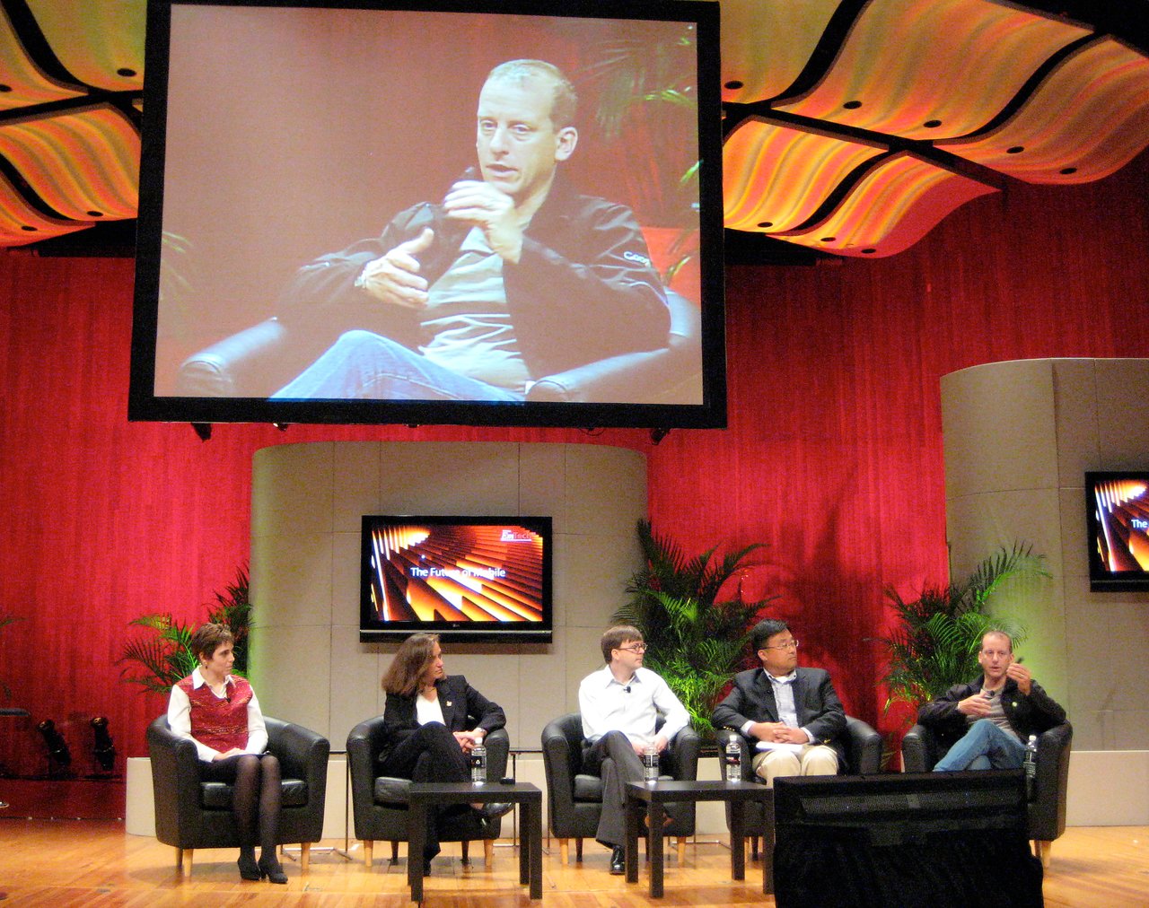Panelists discuss the future of mobile technology on stage at EmTech 2008, with a speaker shown on screen.